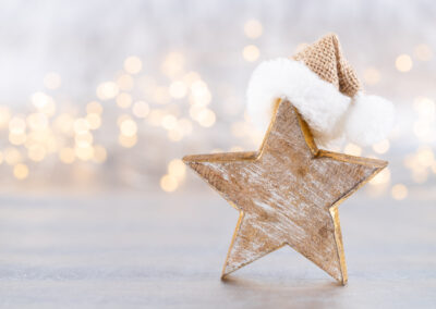 Ein Weihnachtsstern aus Holz mit Mütze vor Lichterbokeh